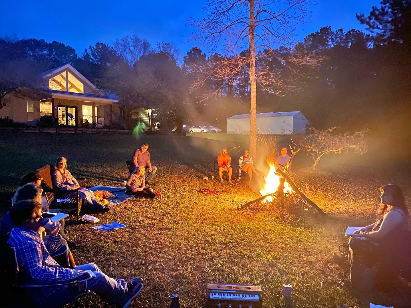 People seated together around a fire at dusk
