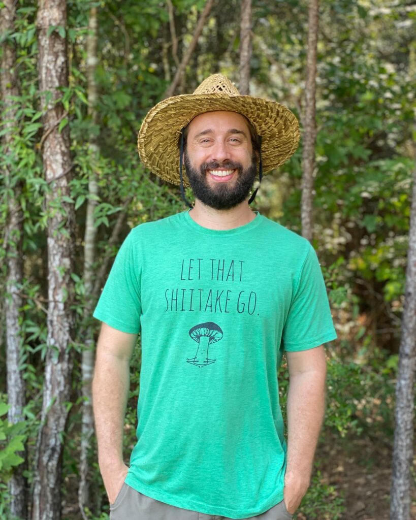 Joshua Riley standing outside in a straw hat