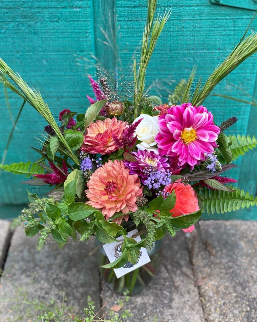 Colorful flowers arranged in a vase against a turquoise wall