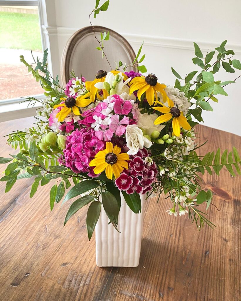 Pink and yellow flowers arranged in a white vase